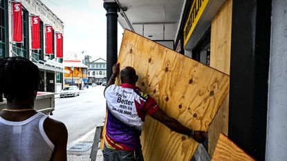 Man boards up shop window in Bridgetown, Barbados, before Hurricane Beryl