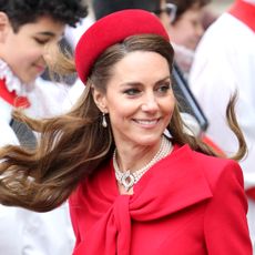 Kate Middleton wearing a red dress and hat smiling