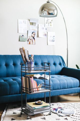 a blue sofa with a storage trolley in front