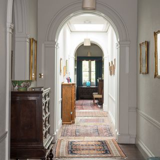 corridor with white wall and wooden floor with rugs