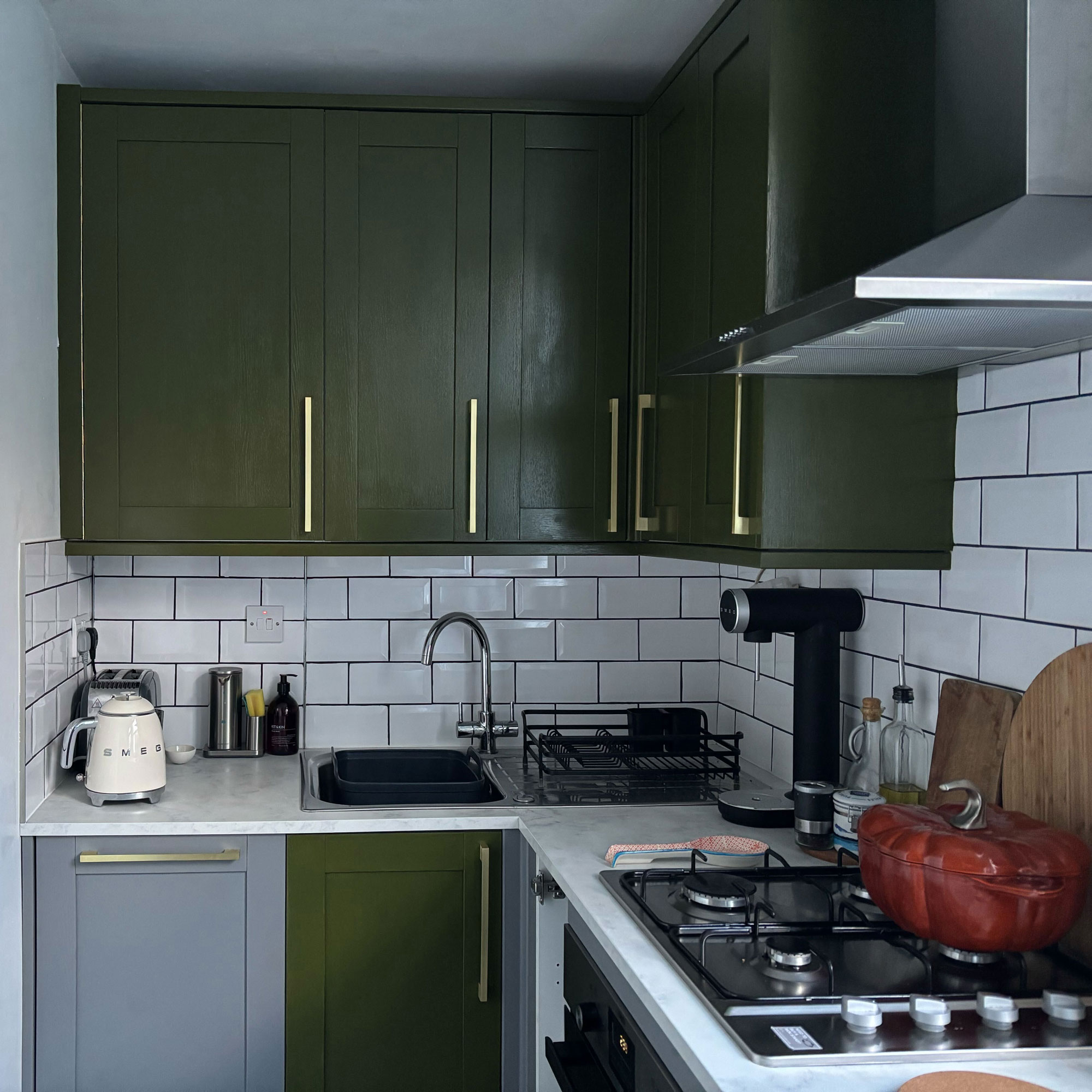 Green painted kitchen with gold handles and white countertops