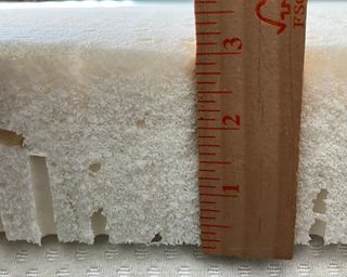 A brown ruler being used to measure Turmerry latex mattress topper