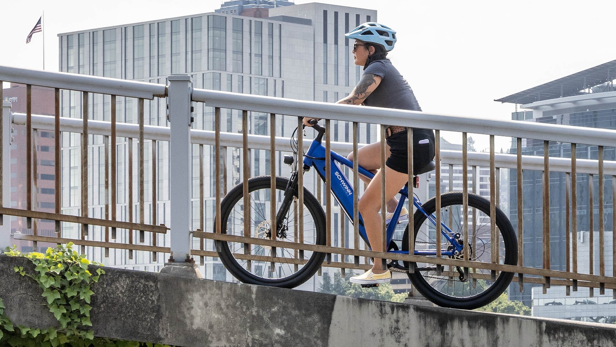 Wanita mengendarai sepeda elektronik Schwinn Marshall di jembatan
