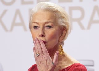 Helen Mirren blowing a kiss to a crowd with her tiny tattoo visible on her hand