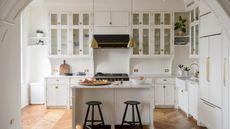 Fitted white country kitchen through period archway with kitchen island and brass fittings on parquet floor
