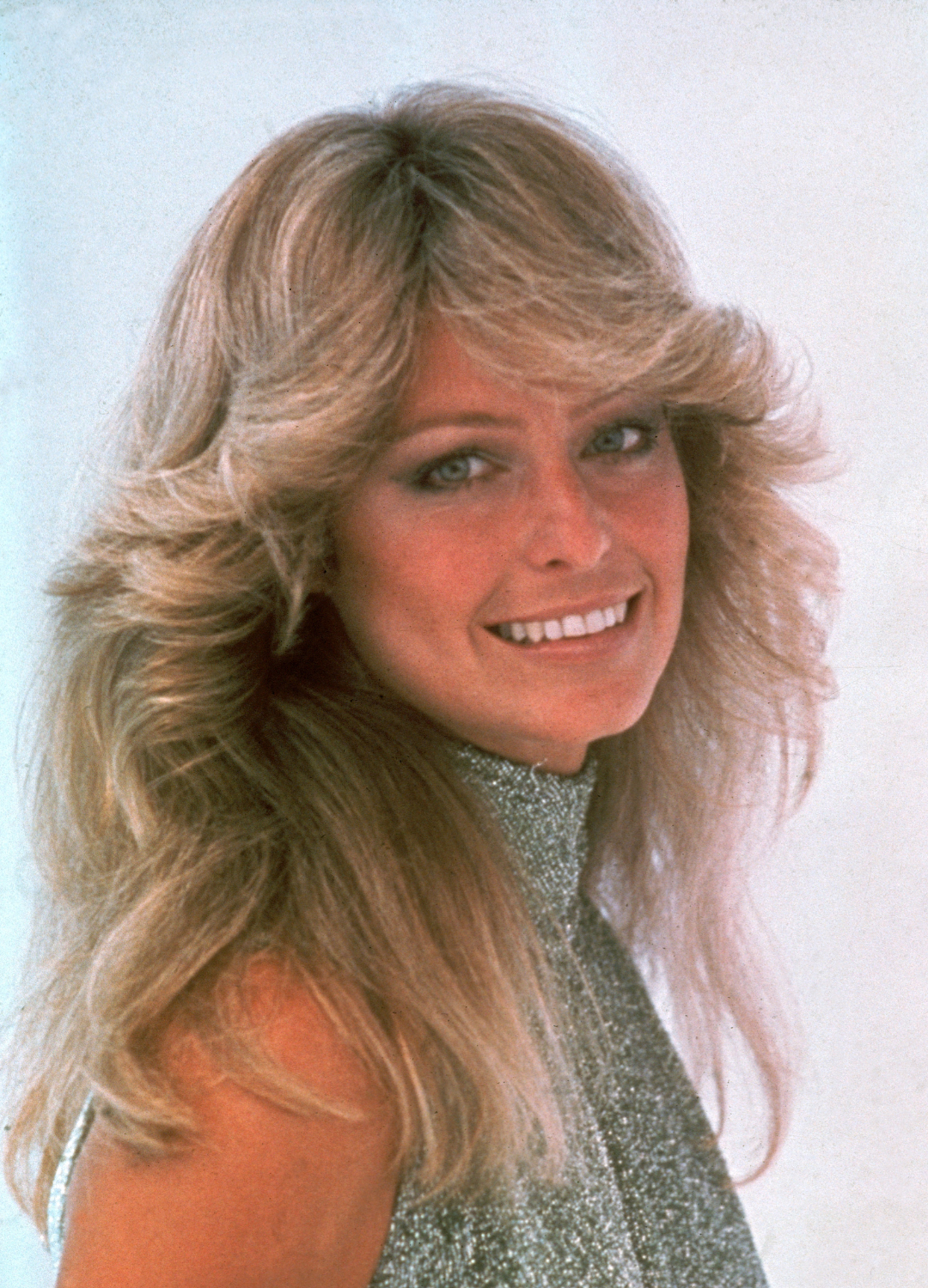 Portrait of American actress Farrah Fawcett, dressed in a high-necked, sleeveless outfit, June 1977