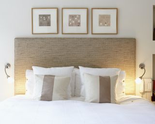A white bed made up with symmetrical light sconces and pillows