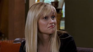 Reese Witherspoon sits on a couch and looks spunky in a screenshot from Four Christmases