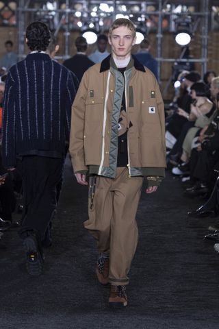 Man on Sacai runway in Carharrt workwear-inspired jacket and trousers