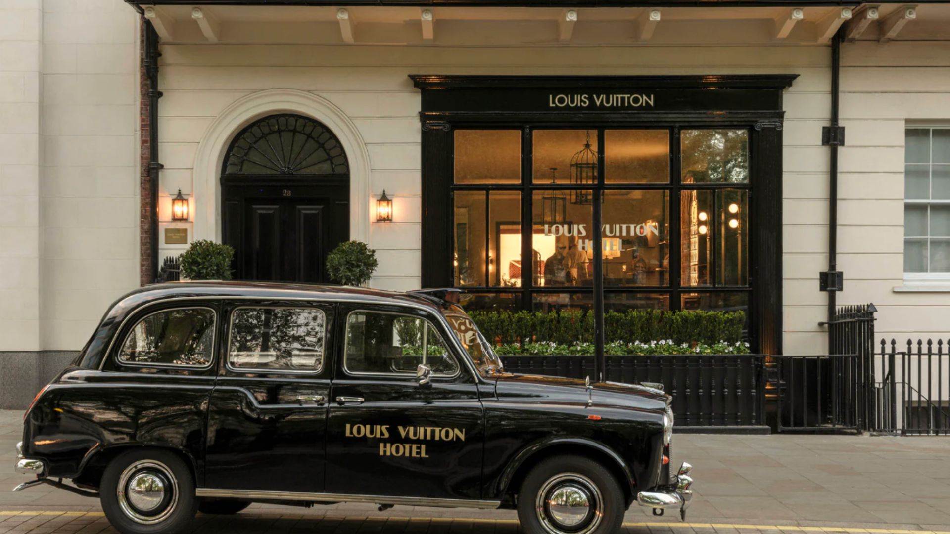an image of the exterior of the hotel with a LV branded black cab outside 