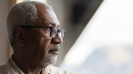 Senior man looks thoughtfully out of window