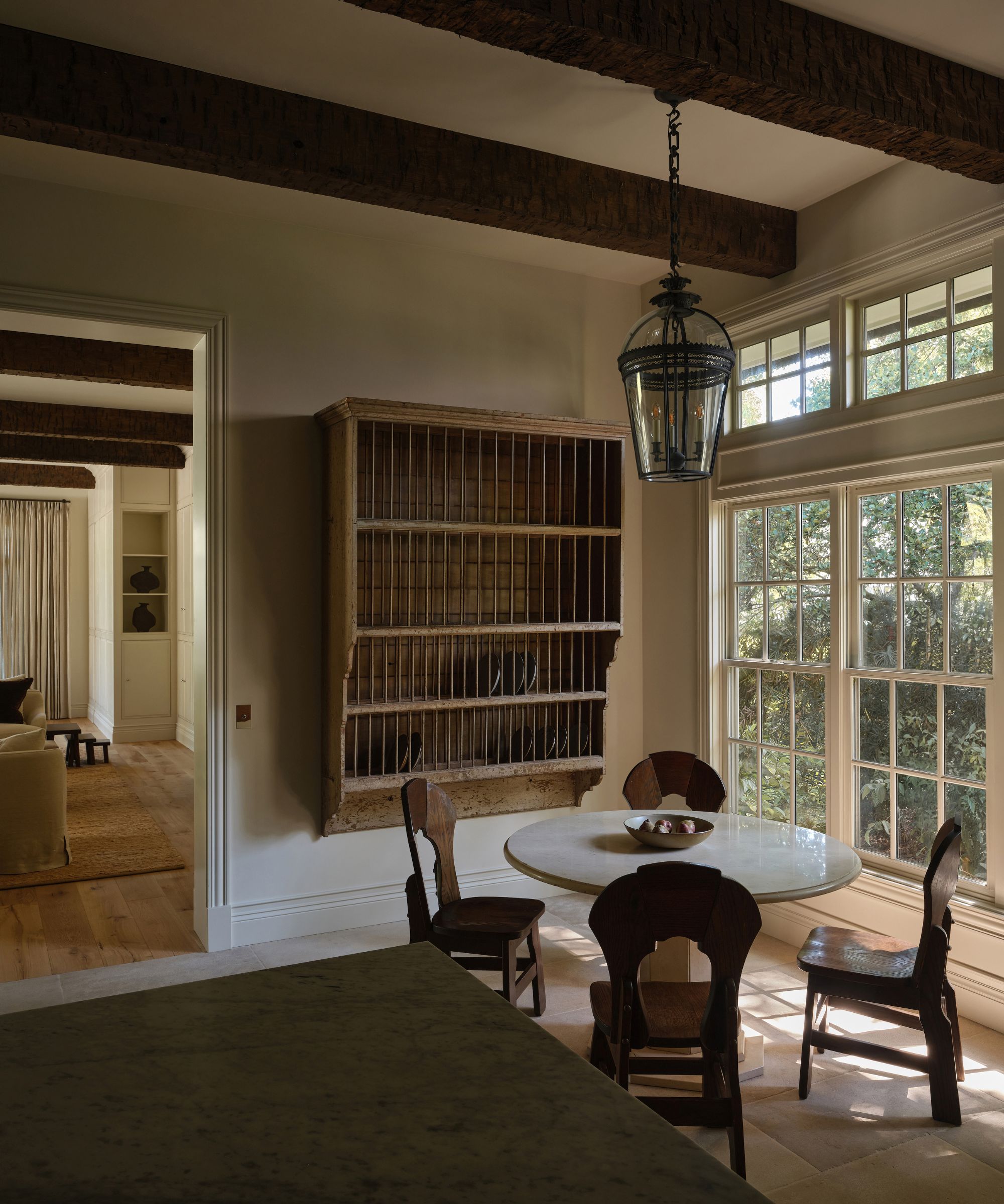 Cozy corner of large kitchen, round marble table with wooden chairs, large wooden plate rack