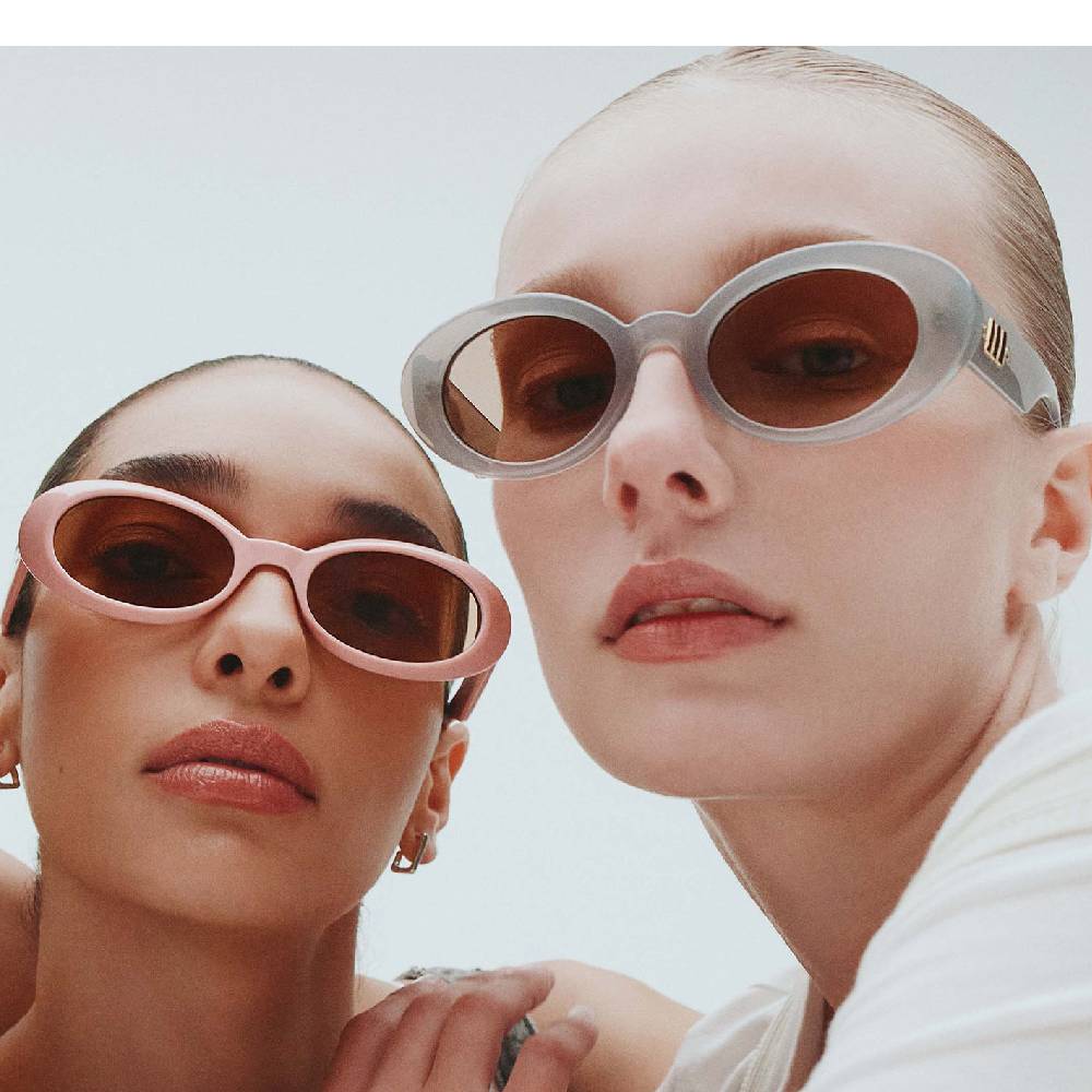 Two models wearing modern, round sunglasses from Le Specs.