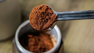 Coffee grounds in a scoop over a coffee jar