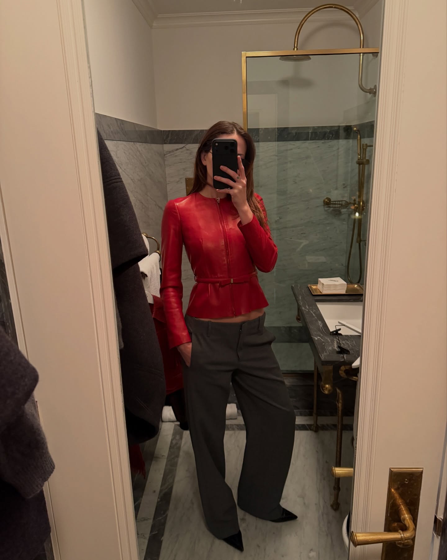 a woman wearing a red jacket in front of a mirror posing with her phone