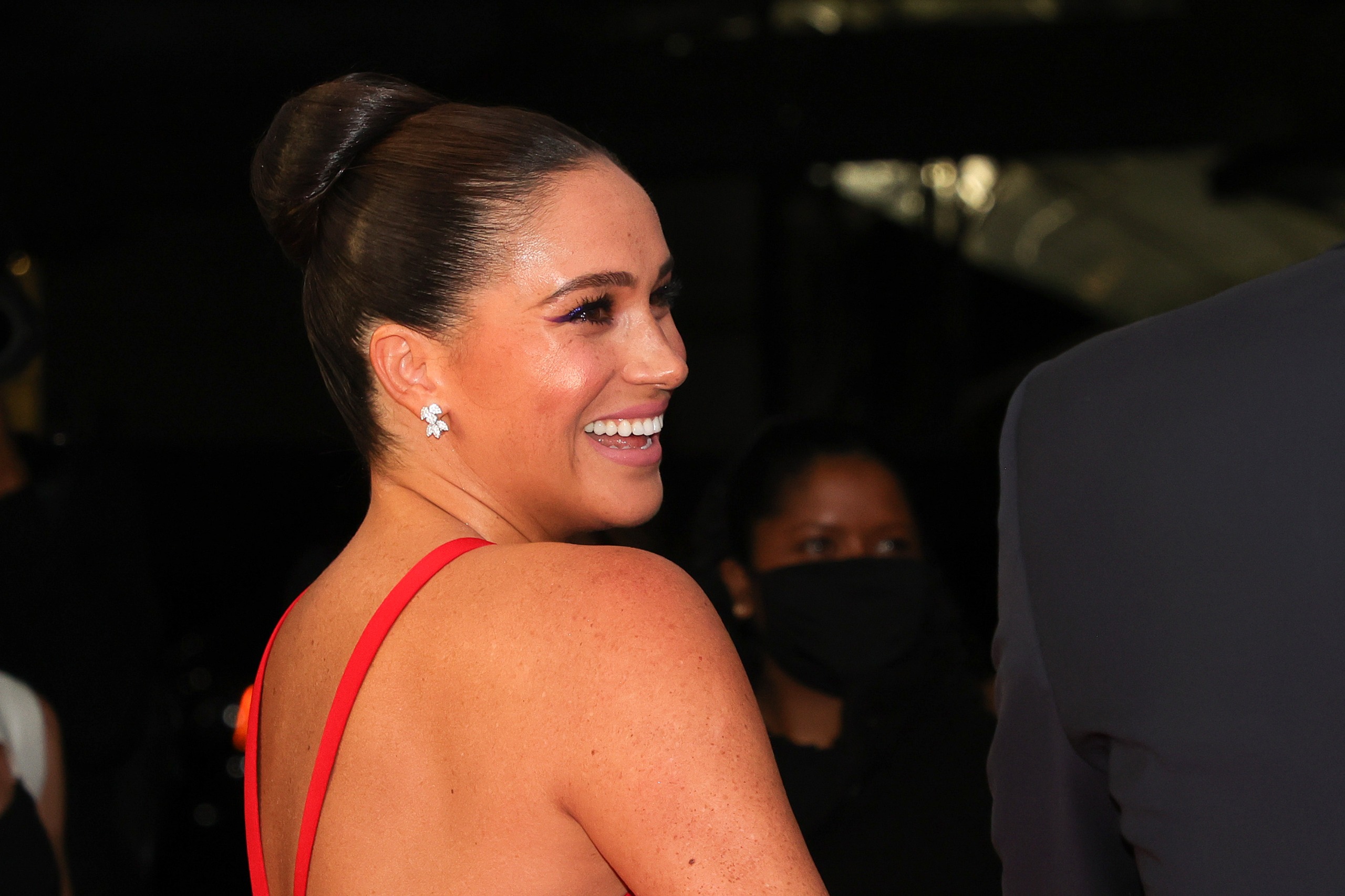 Meghan Markle wearing a red strappy dress and smiling