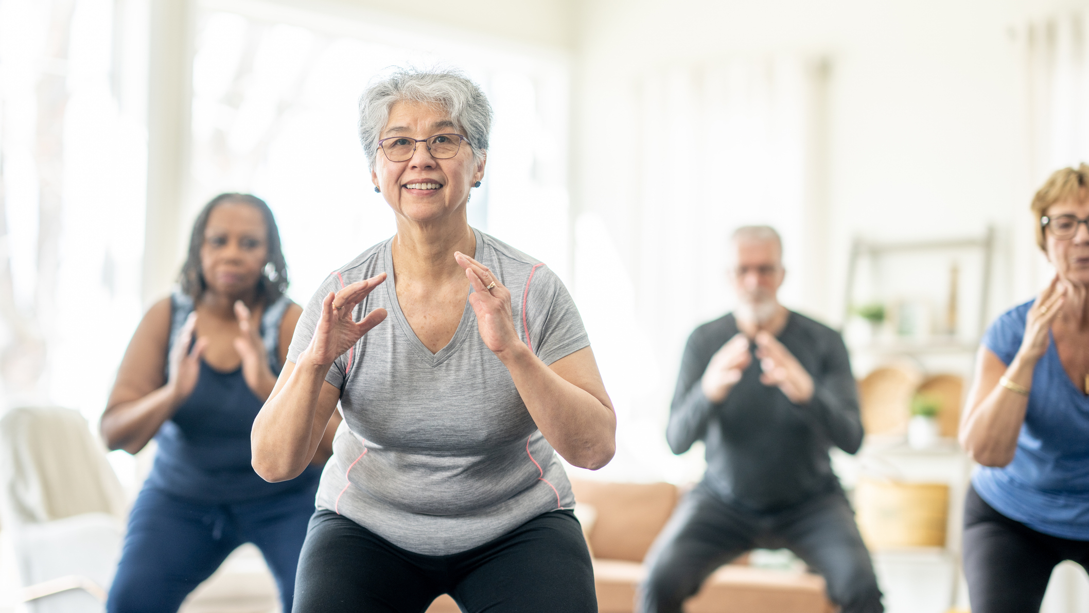 Group of four seniors exercising in domestic setting
