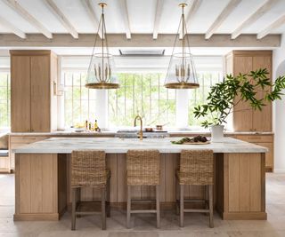 A wood kitchen with marble countertops and two statement pendant lights