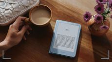 Kindle Aluminium on a wooden table with a cup of tea