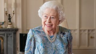Queen Elizabeth II smiling, in a floral blue dress at Windsor Castle (April 2022)
