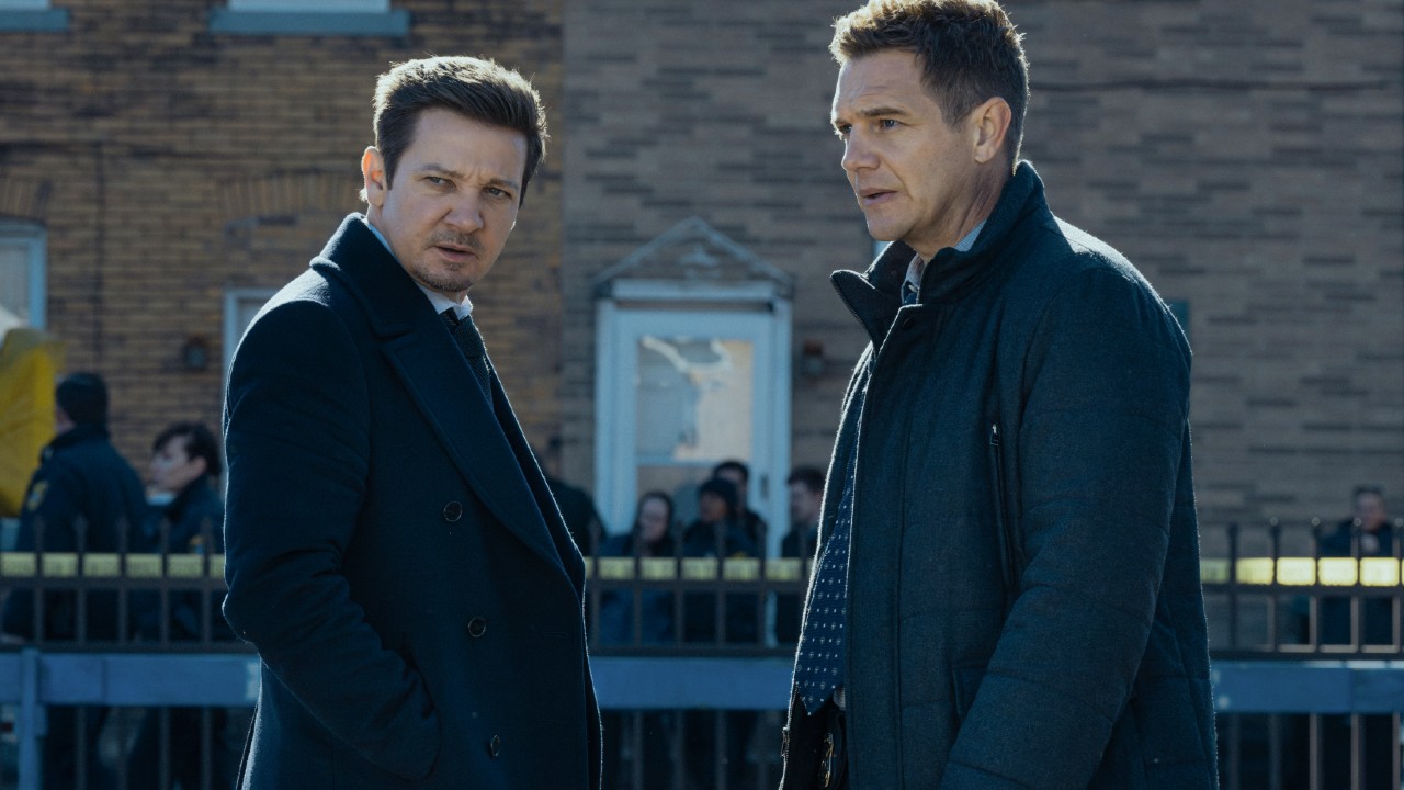 L-R: Jeremy Renner as Mike McLusky and Taylor Handley as Kyle McLusky facing each other while both looking at what it to their left.