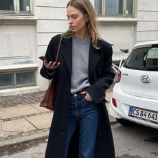 woman in gray sweater, coat, and jeans