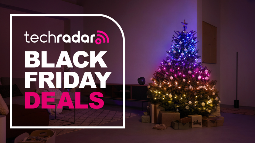 The Philips Hue Festavia string lights are pictured decorating a Christmas tree in a living room. To the right is a large badge which reads &quot;Tech Radar Black Friday Deals&quot;.