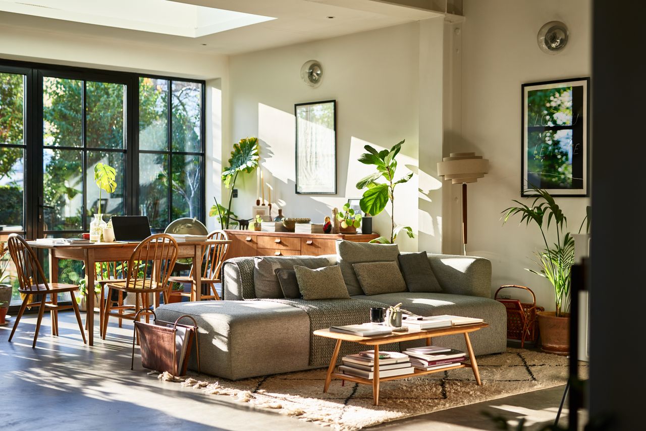 Comfortable living room with sofa and coffee table, dining table and chairs, with patio doors leading into garden