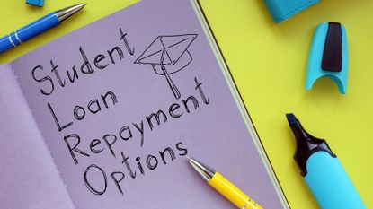 A notebook reading "student loan repayment options" sitting on a desk with pens