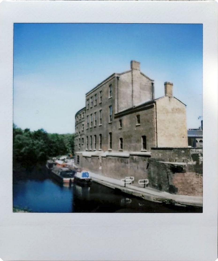Digitized instant photo taken with the Fujifilm Instax SQ40 of old building along a canal on sunny day