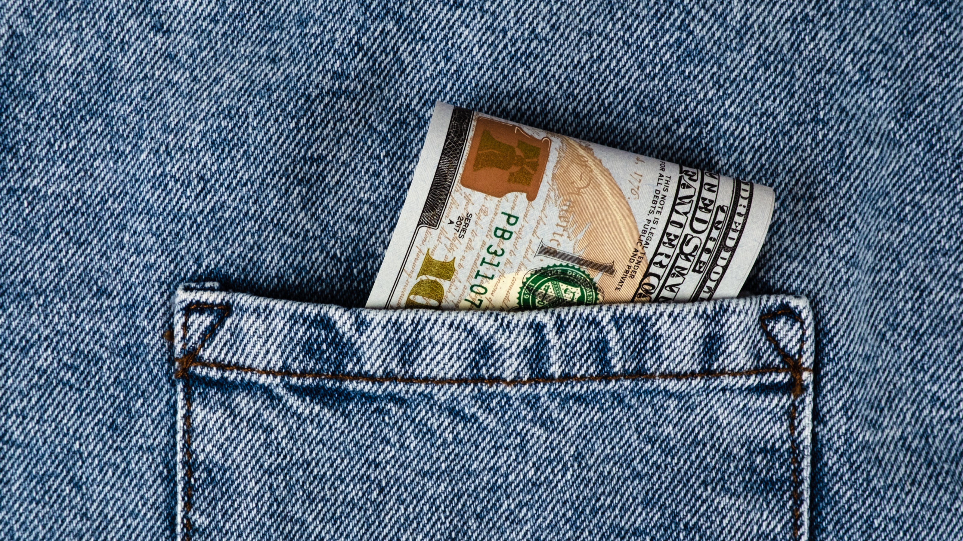 Money folded up in a denim pocket.
