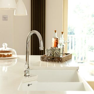 kitchen with ceramic sink steel tap wooden tray and white worktop