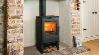 log burning stove in large fireplace with exposed bricks