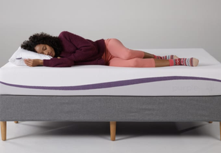 A woman lies on her side on the Purple Mattress