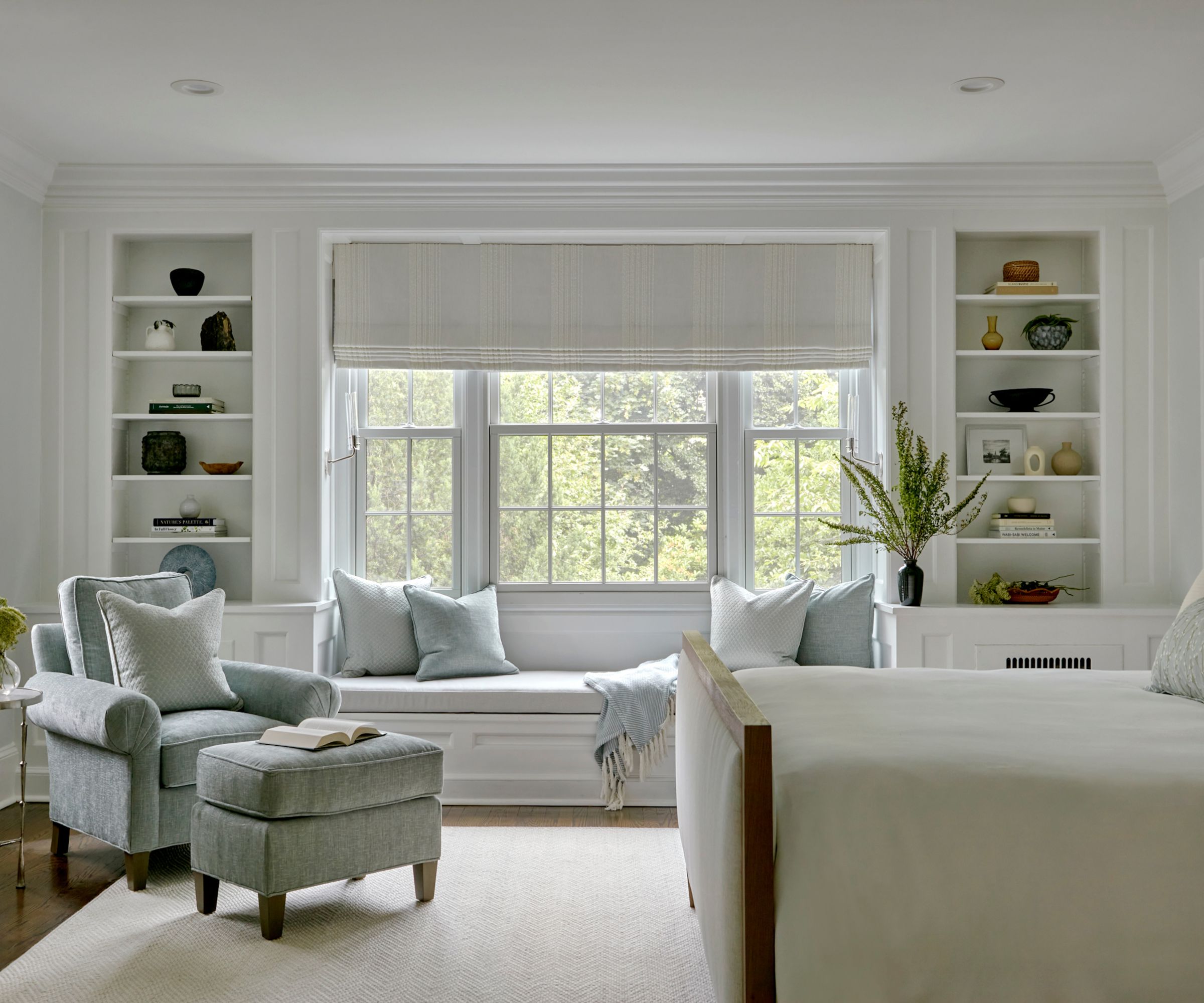 neutral bedroom with white walls, large window with window seat, light blue cushions