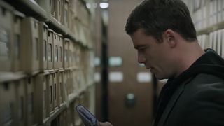 Gabriel Basso as Peter Sutherland looking at his phone during The Night Agent season 2.