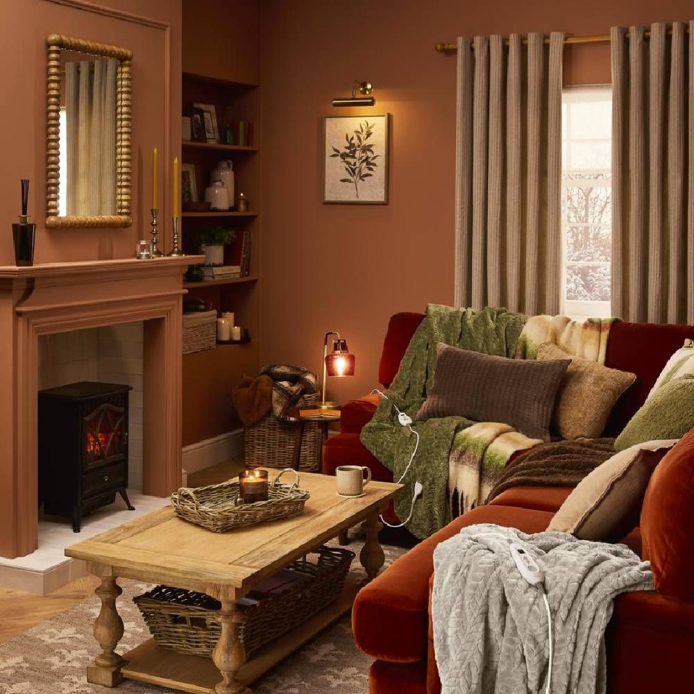 A cosy, deep orange-terracotta lounge, with a deep red sofa, and a wooden coffee table from Dunelm.
