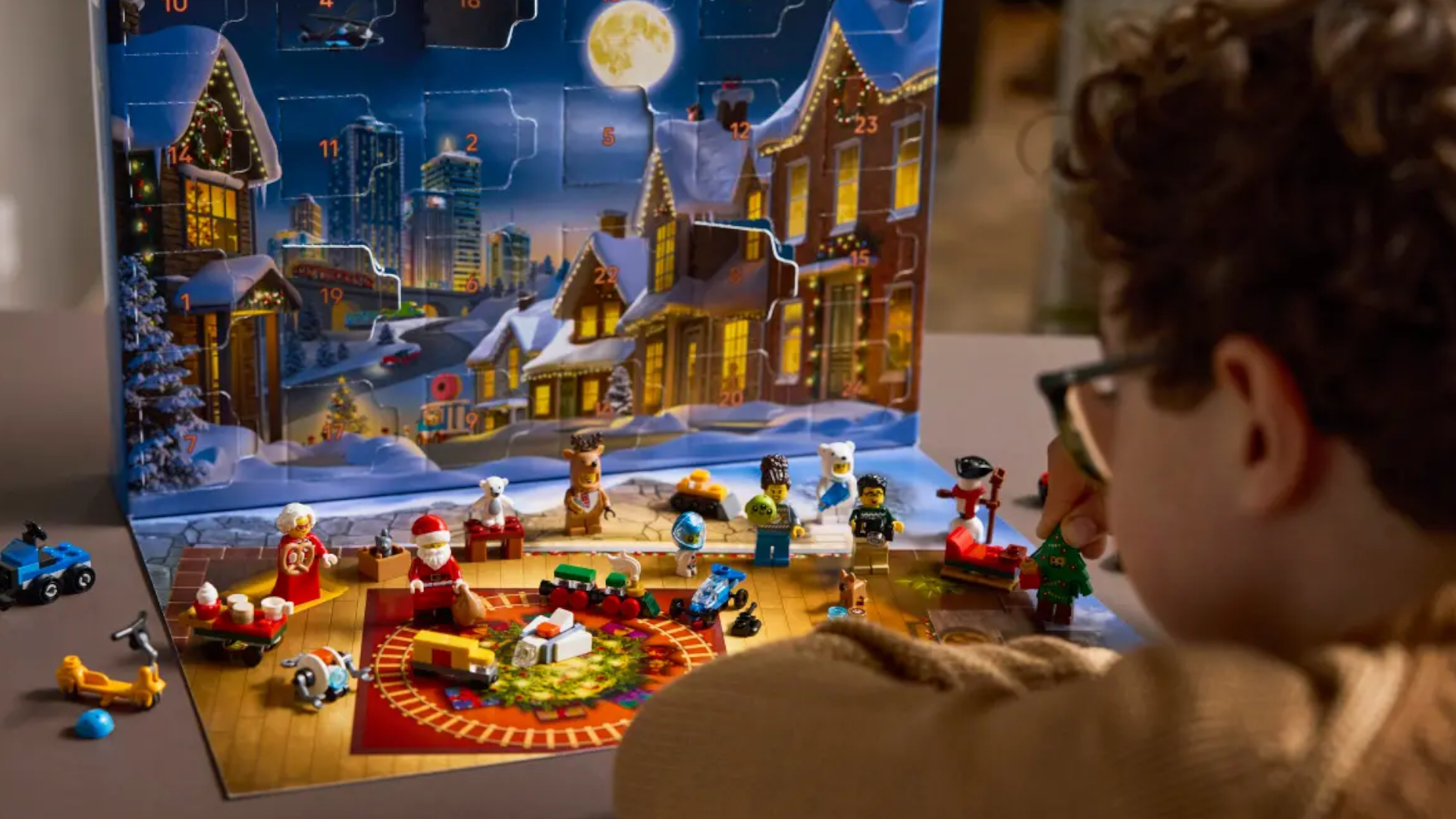 A boy with glasses looks at the Lego City Advent Calendar and figures