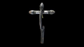 A silver brooch with a C-shaped outward facing curve against a cross-like structure, as if it were a crossbow. It is against a black background.