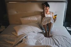 Worried woman sitting on bed looking at phone