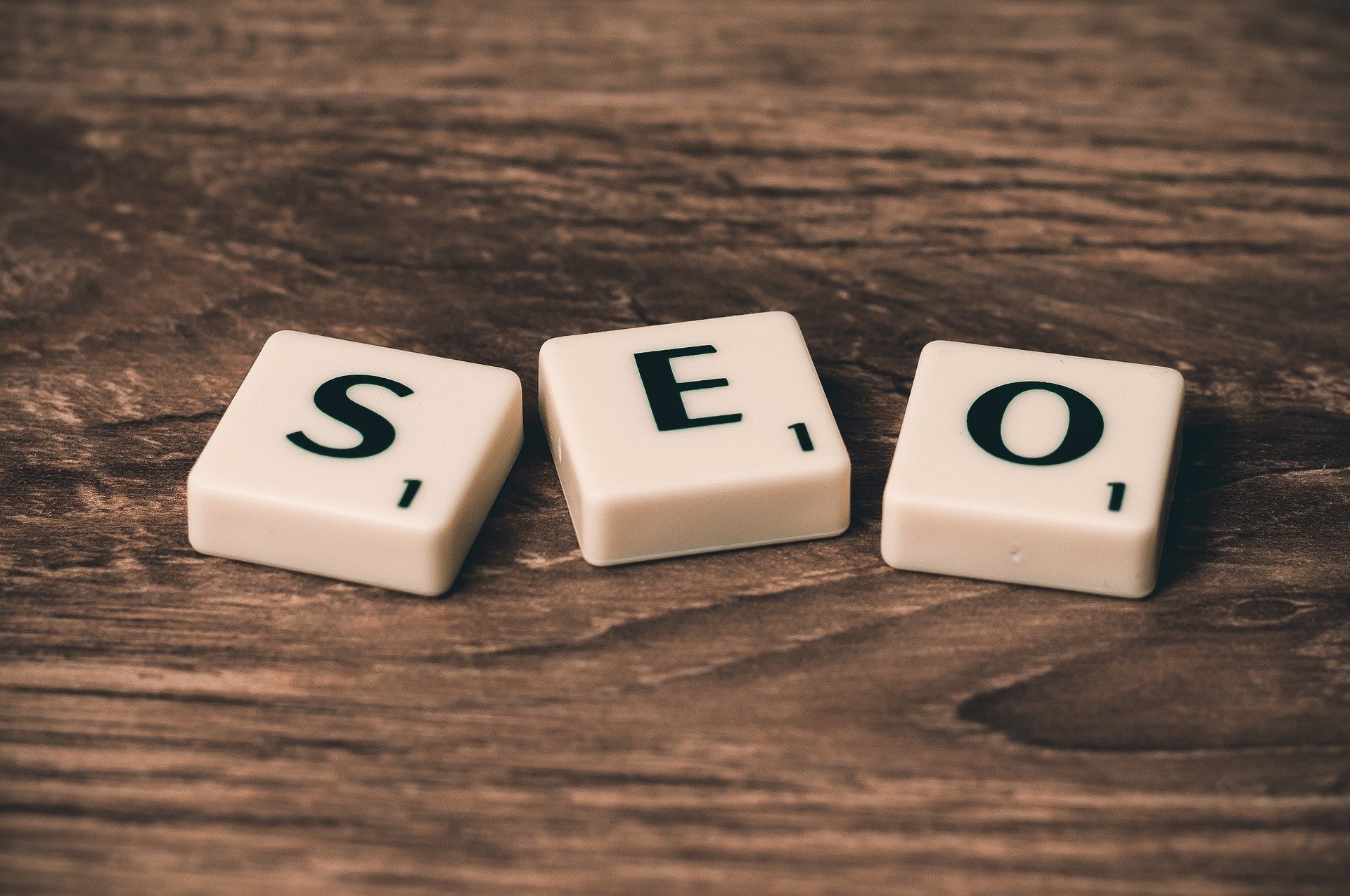 Three scrabble tiles spelling SEO laid out on a wooden table