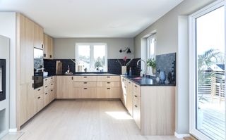 u shaped kitchen with black worktops and wood cupboards