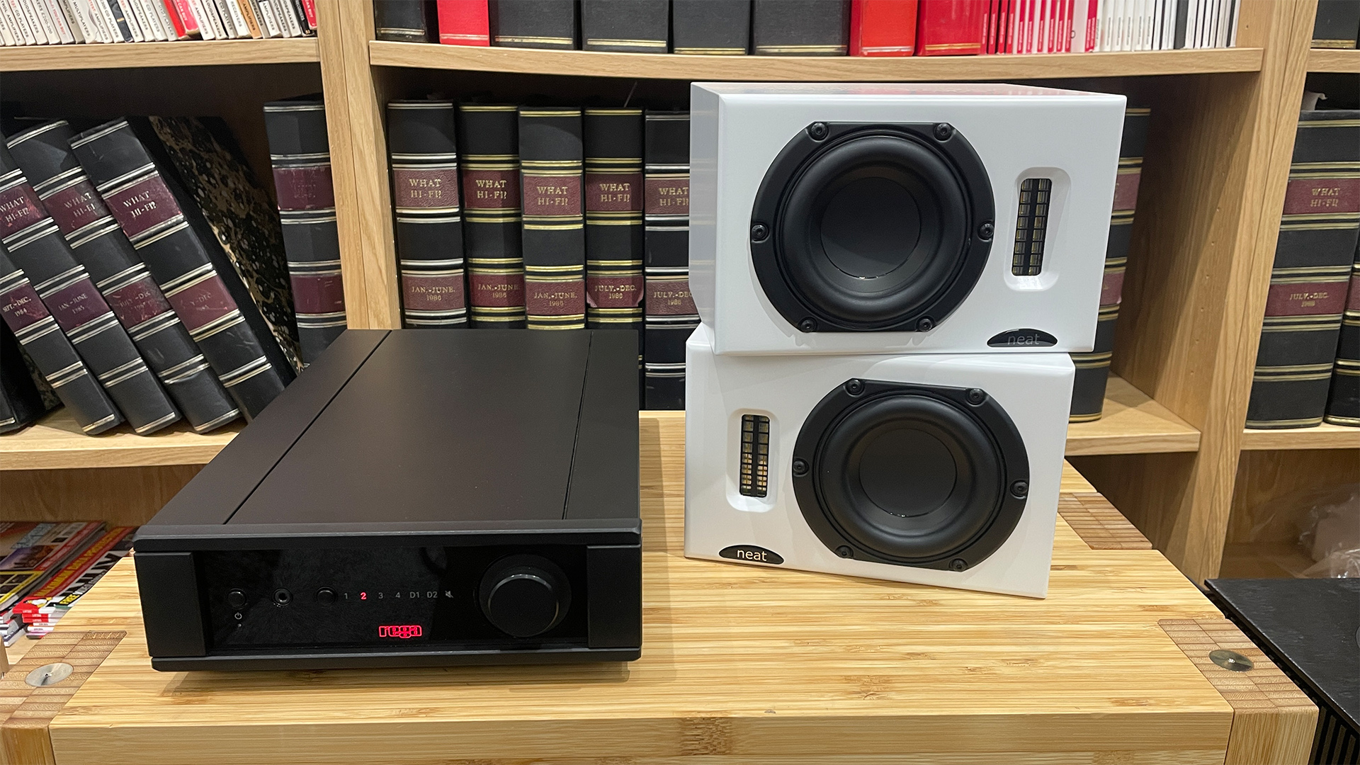 Neat Iota II speakers placed next to Rega Brio Mk7 amp on wooden shelf