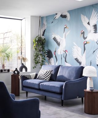 Mid-dark blue sofa in lounge with blue, bird inspired feature wallpaper.