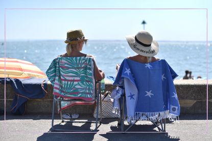 Two women sat in deckchairs facing the sea
