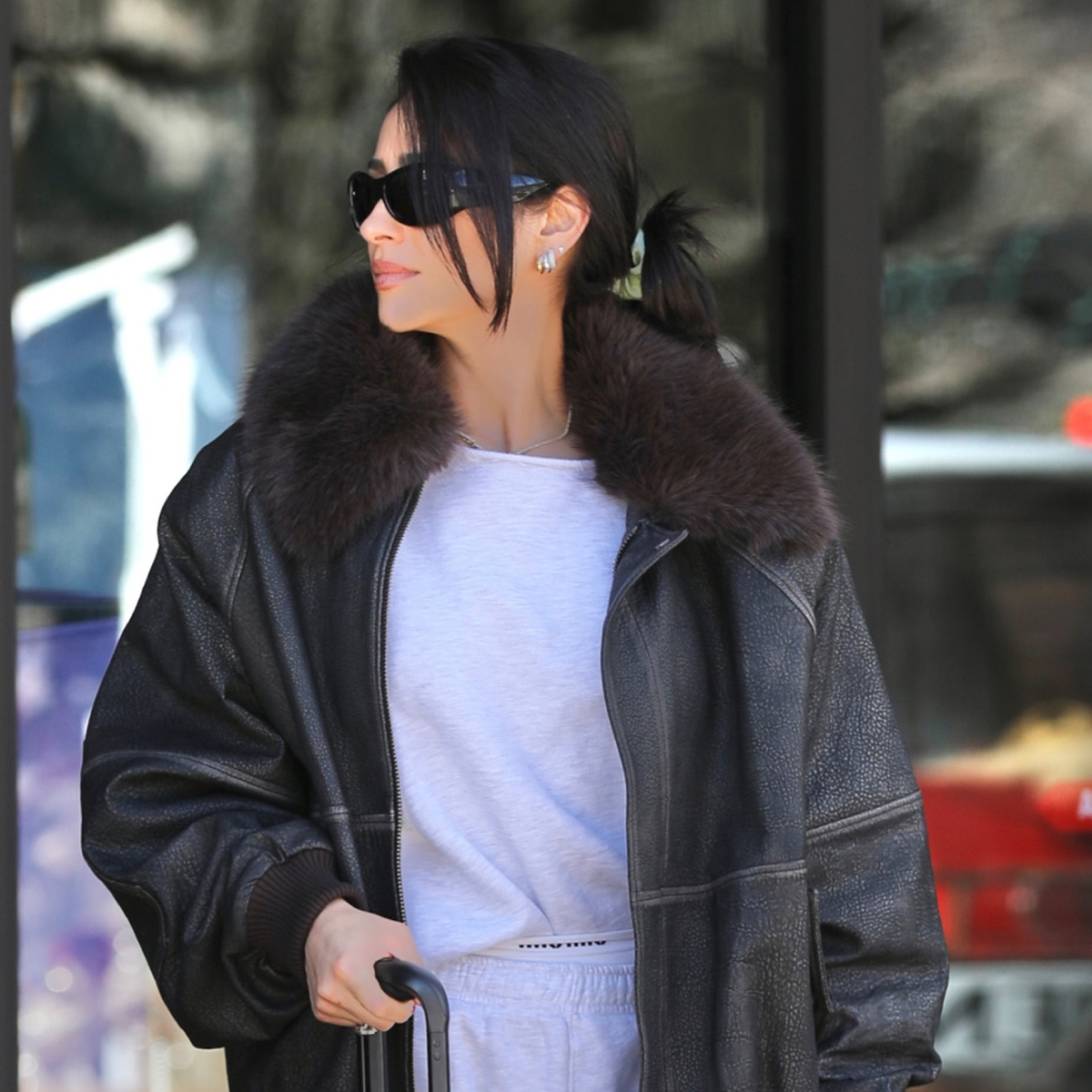 Shay mitchell wears a fur-trimmed leather coat with a gray sweatshirt.