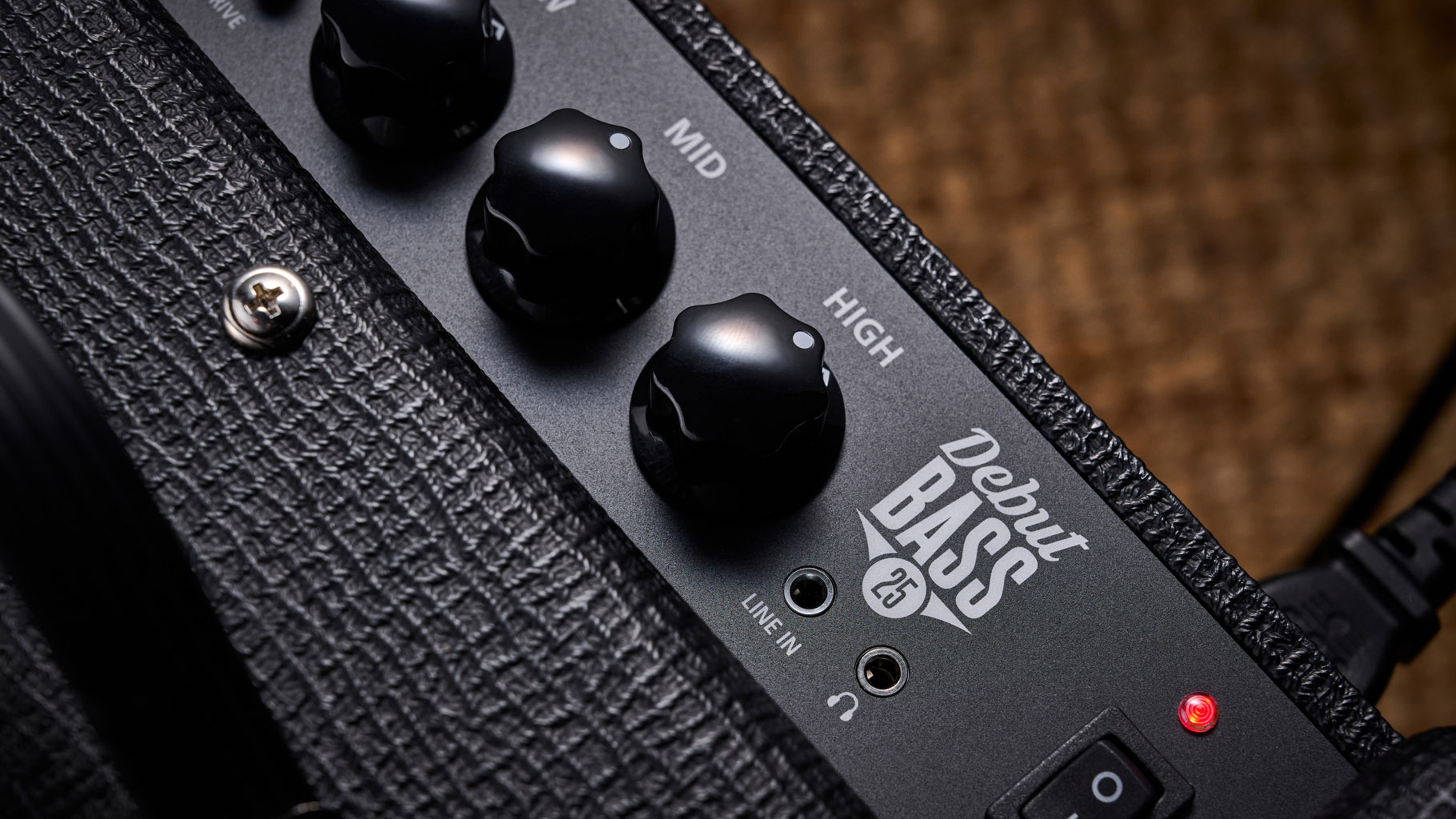 Blackstar Debut Bass 25: this compact little combo is finished in black with matching grille clothe and is photographed in close-up against a stone floor and weaved rug.