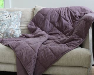 Purple weighted blanket draped on sofa