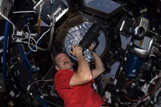 Canadian astronaut Chris Hadfield poses with a camera in the Cupola of the International Space Station, which serves as the observation deck, during the Expedition 34 mission in January 2013.