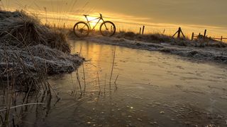 Bike reflected in icy puddle at dawn